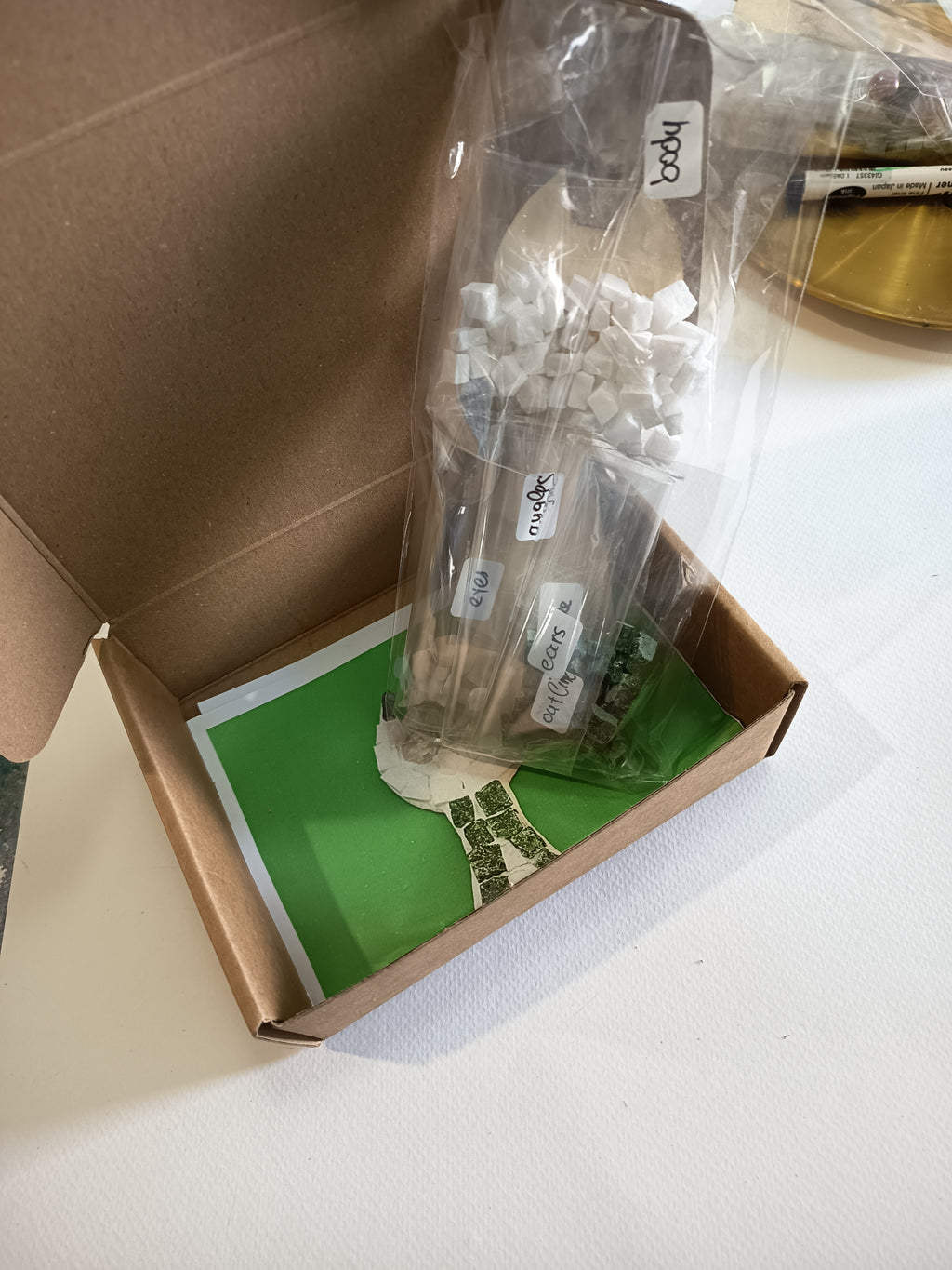 DIY mosaic cat kit contents - wooden cat base, hand-cut Greek marble tiles (square and triangle), border in your chosen color (red, blue, green, light green or black), eye pieces, wall hook and glue