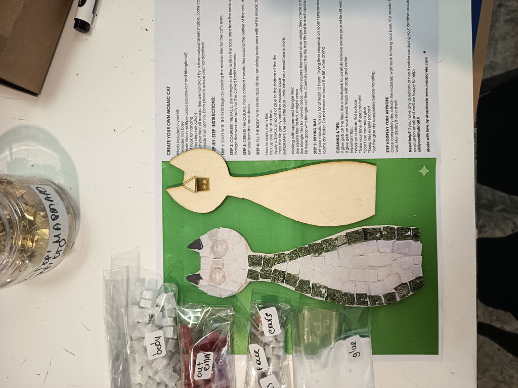 DIY mosaic cat kit contents - wooden cat base, hand-cut Greek marble tiles (square and triangle), border in your chosen color (red, blue, green, light green or black), eye pieces, wall hook and glue