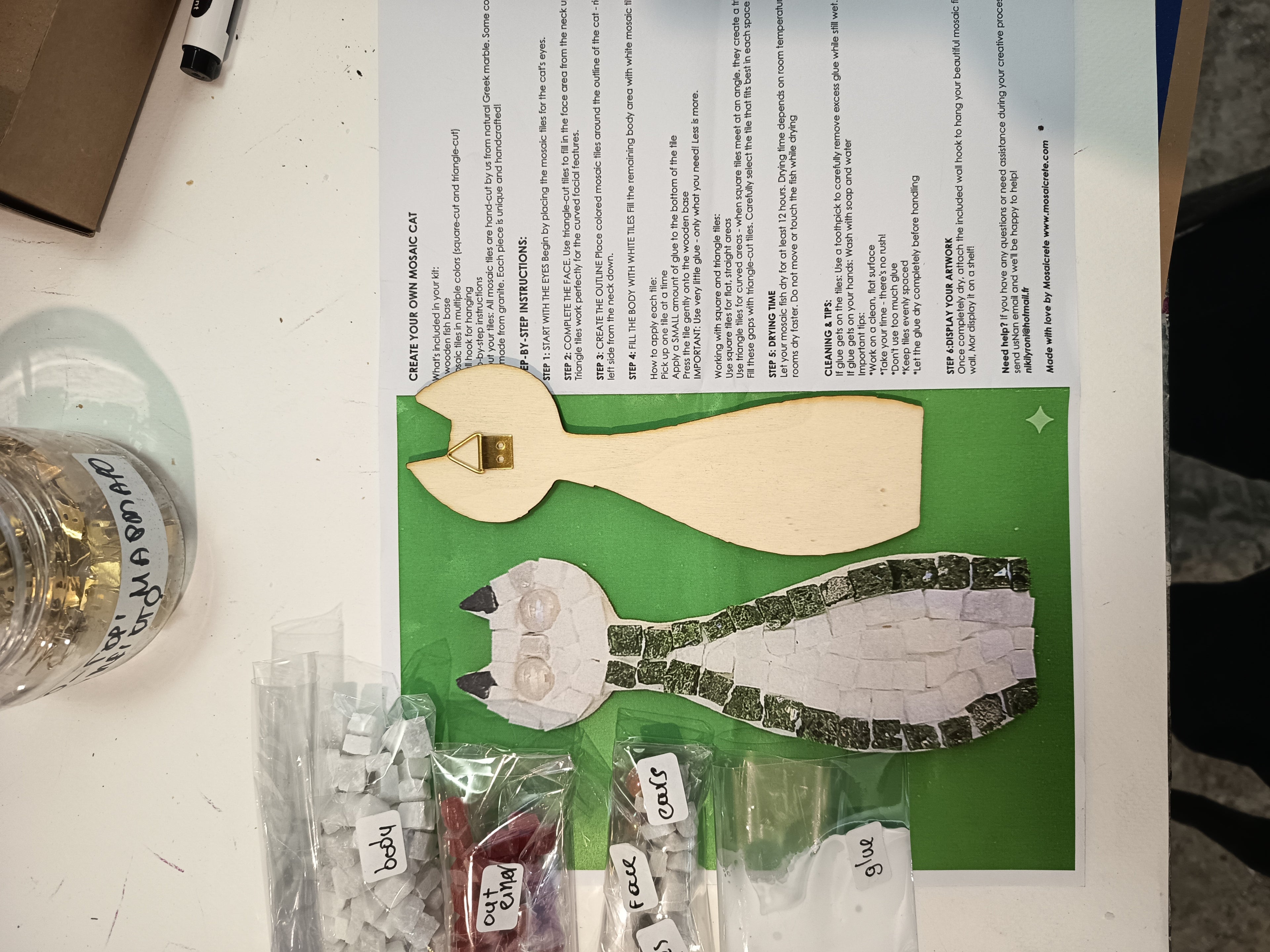 DIY mosaic cat kit contents - wooden cat base, hand-cut Greek marble tiles (square and triangle), border in your chosen color (red, blue, green, light green or black), eye pieces, wall hook and glue
